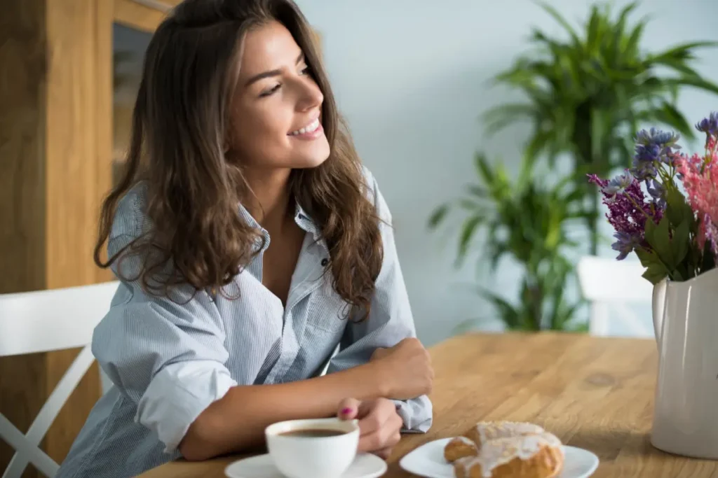 rotina matinal Mulher jovem a beber café na sala de jantar. Imagem do gpointstudio no Freepik.